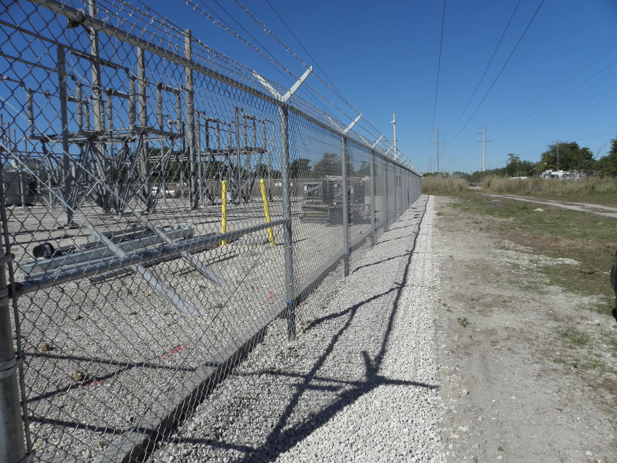 Galvanized chain link fence winding along green lawn and trees