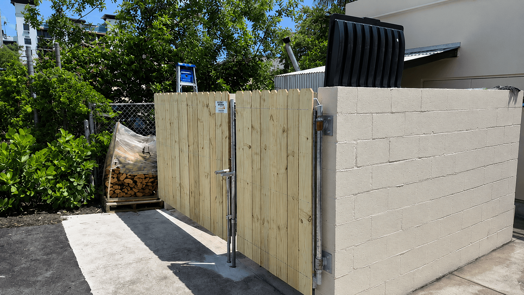 Wood picket gates mounted to a block wall around a waste enclosure