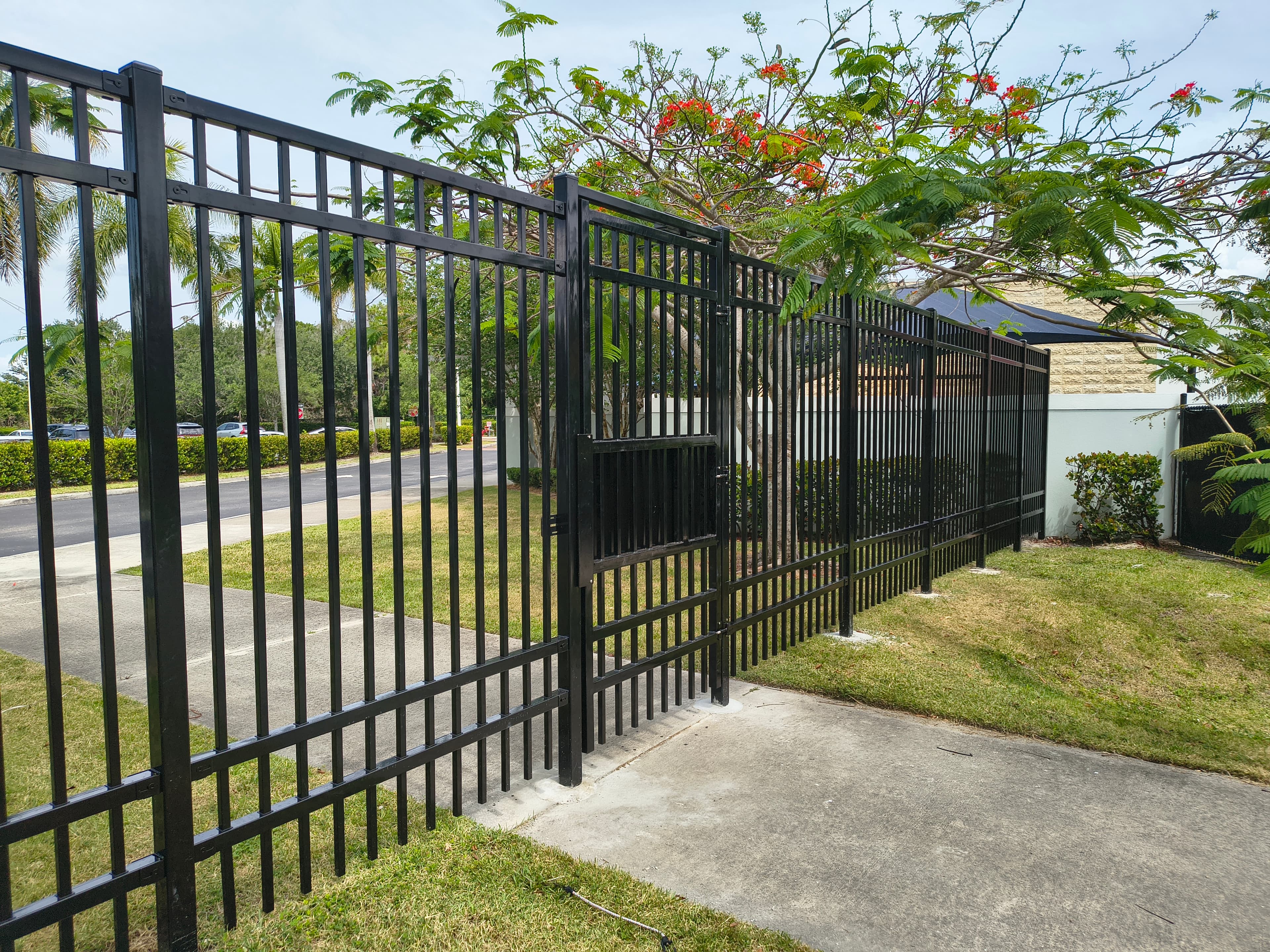 Black ornamental perimeter fence with pedestrian gate at a park or school facility